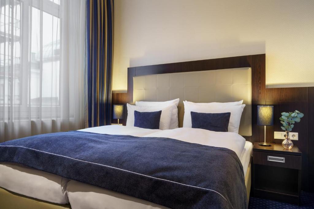 a bedroom with a large bed with a blue blanket at Novum Hotel Continental Hamburg Hauptbahnhof in Hamburg
