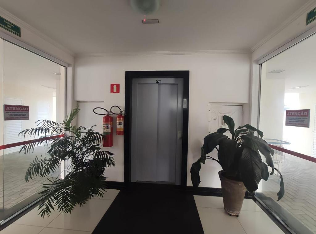 um hall de entrada com uma porta e uma planta em vasos em Apartamento de Luxo acesso a Praia Grande e Praia do Tenório para 6 pessoas em Ubatuba