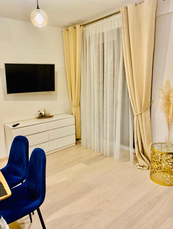 a living room with a television and a blue chair at Apartamentai “Viola” Juodkranteje in Juodkrantė