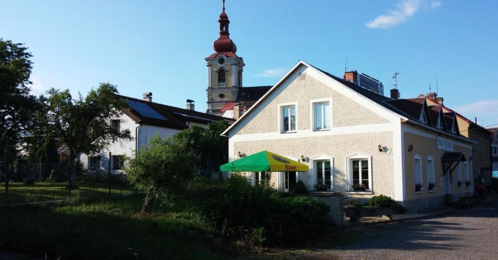 a white house with a green and yellow umbrella at Pension U Milana in Dvůr Králové nad Labem