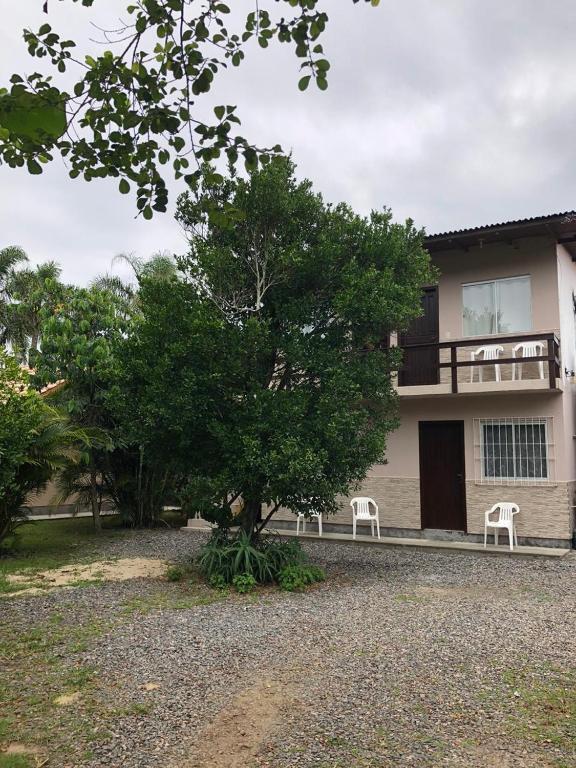 ein Haus mit zwei weißen Stühlen und einem Baum in der Unterkunft Apartamentos Neia in Florianópolis