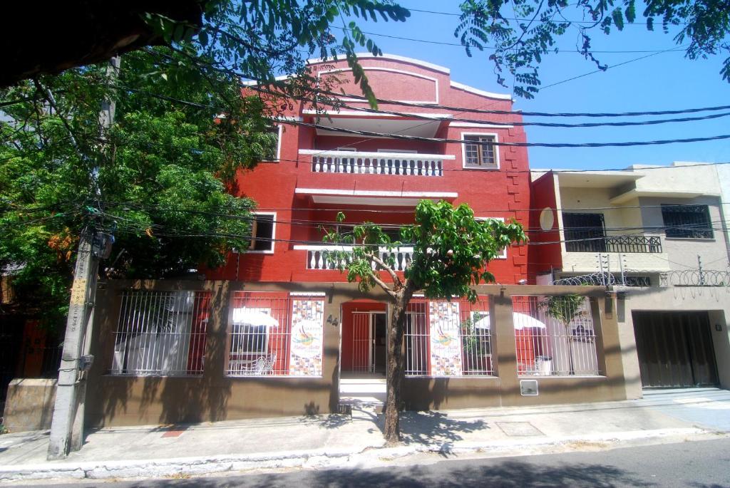 un bâtiment rouge avec un arbre devant lui dans l'établissement Refúgio Pousada Fortaleza, à Fortaleza