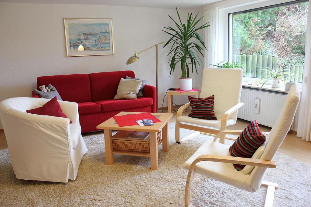 a living room with a red couch and two chairs at Ferienwohnung Valentin in Glücksburg