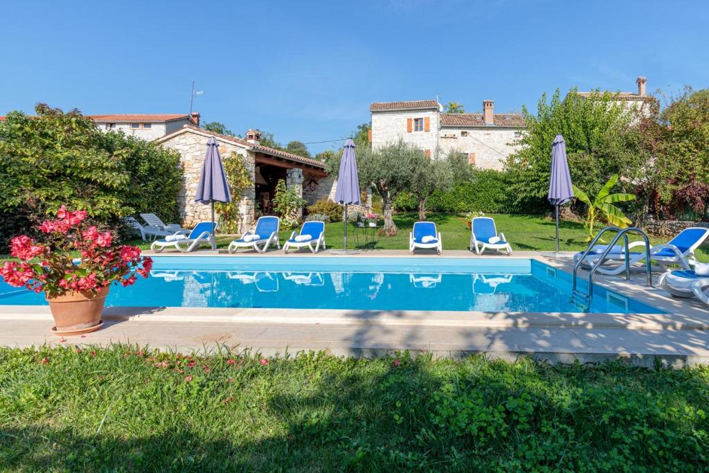 una piscina con sedie e ombrelloni blu di Holiday Home Tamaris with Pool a Višnjan (Visignano)