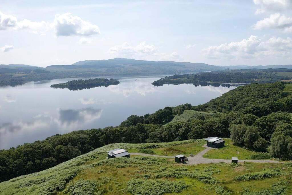 a view of a lake with two huts on a hill at Odhrán Lodge, St Conan's Escape: Home with a view in Loch Awe