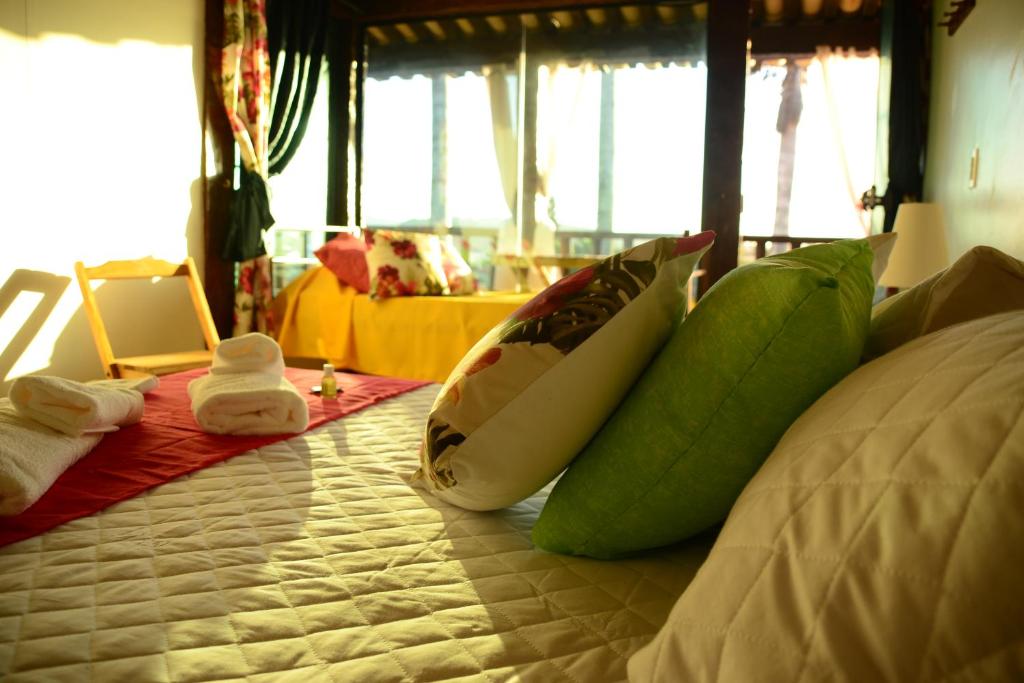 a bed with green and white pillows on it at Mirante de geriba! in Búzios