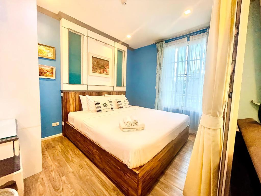 a bedroom with a bed with blue walls and a window at Summer Huahin Condo classic room pool view in Hua Hin