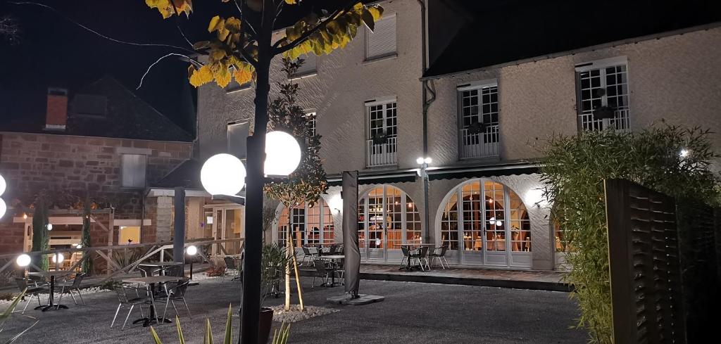 un edificio con mesas y sillas en un patio por la noche en L'Auberge, en Saint-Viance