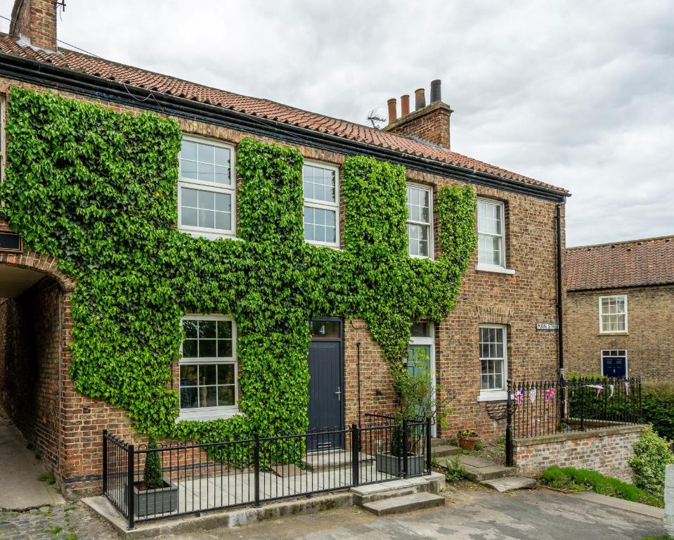 an ivy covered brick house with a blue door at River View, Stamford Bridge in Stamford Bridge