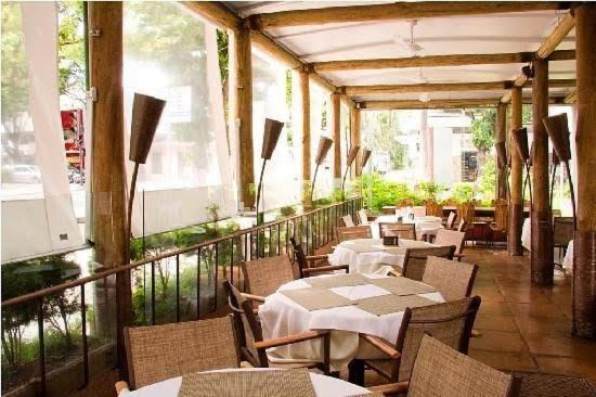um restaurante com mesas e cadeiras e uma varanda em Apart hotel Champagnat em Belo Horizonte