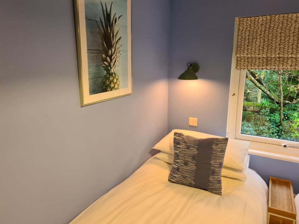 a bedroom with a bed with a window and a pillow at Pebble Cottage in Uny Lelant
