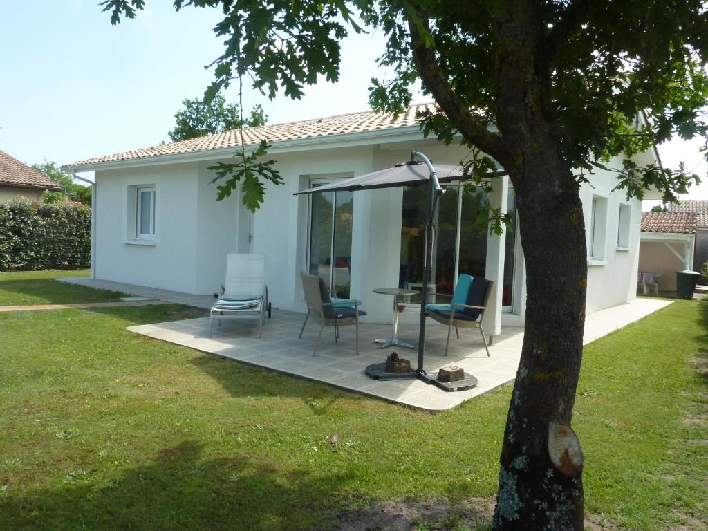 a patio with chairs and an umbrella in front of a house at Villa HESTIA in Le Teich