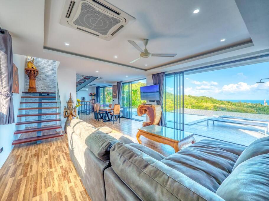 a living room with a large couch and a pool at Reef View Villa in Lamai