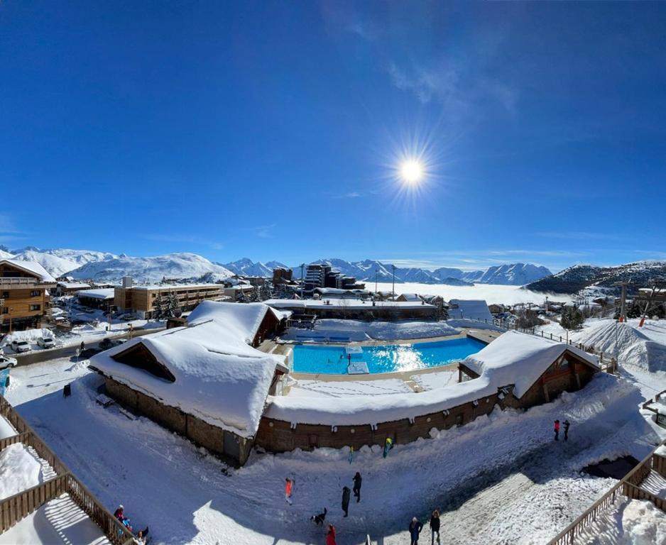 un complexe dans la neige avec des gens qui se promènent autour de lui dans l'établissement Superbe Studio avec vue exceptionnelle, à L'Alpe-d'Huez