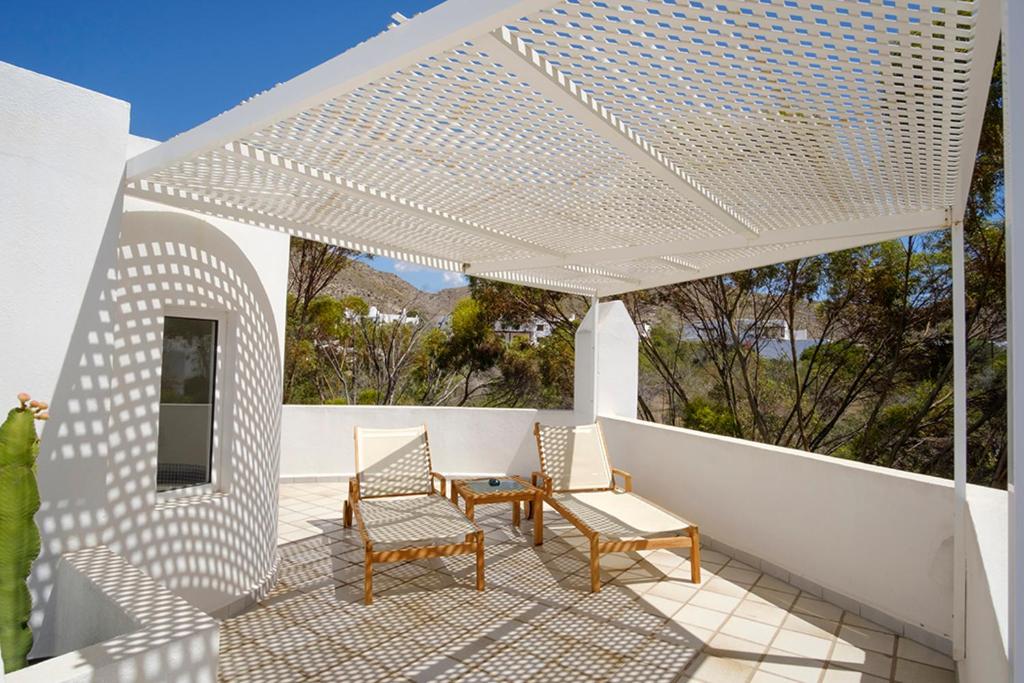 a white pergola on a patio with chairs and a table at miKasa Agua Amarga & SPA in Agua Amarga