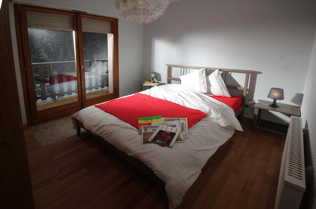 a bedroom with a bed with red and white sheets and a window at Appartement Adélaïde in Le Hohwald