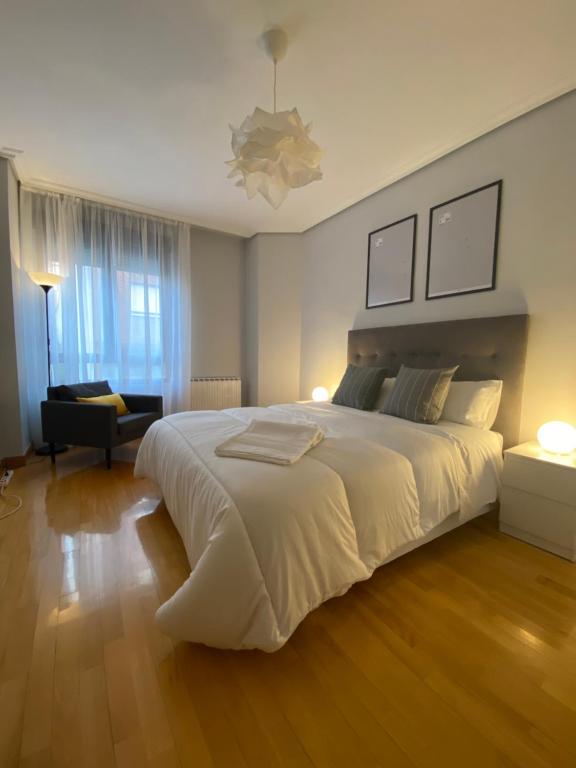 a bedroom with a large white bed and a couch at Apartamento Albelda Centro in Albelda de Iregua