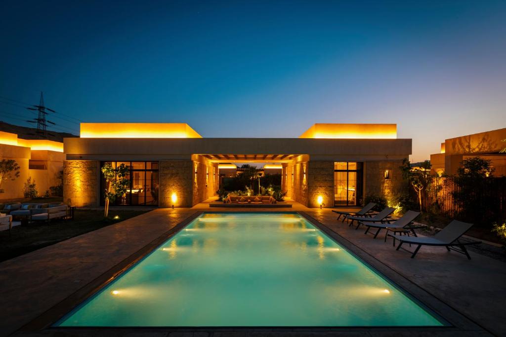 a swimming pool in front of a building at night at The Valley Resort in Riyadh