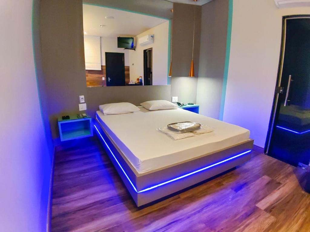 a bedroom with a white bed with a blue light at Motel Caribe in Belo Horizonte