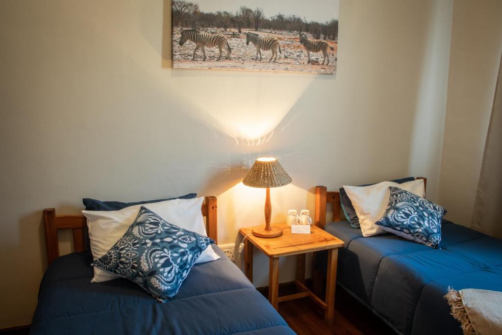 a room with two beds and a table with a lamp at The Mole Guesthouse in Swakopmund