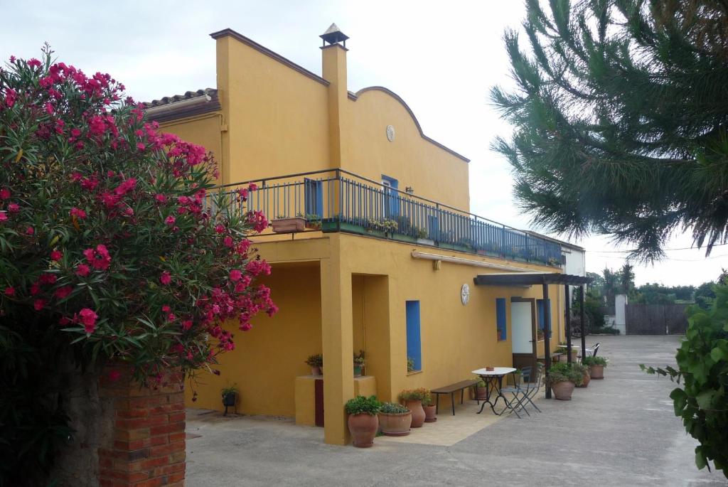 un edificio amarillo con balcón, mesas y flores en Can Selleretas, en Vilamacolum