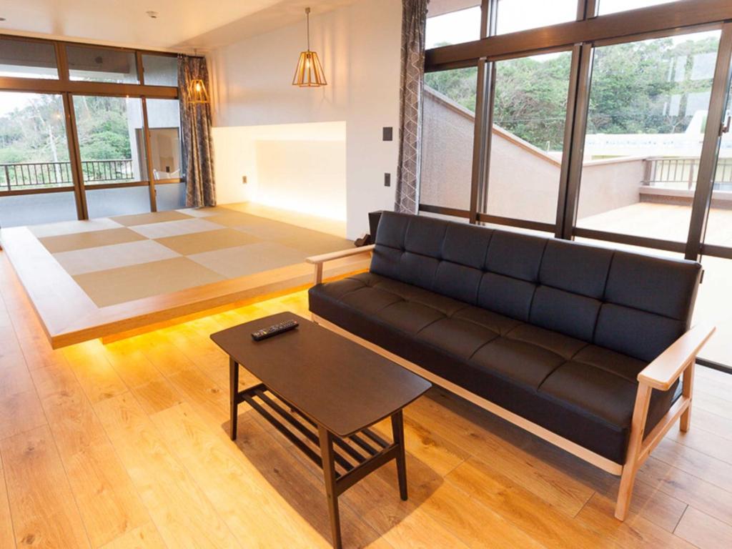 a living room with a black couch and a table at n-house - Vacation STAY 91411v in Nago
