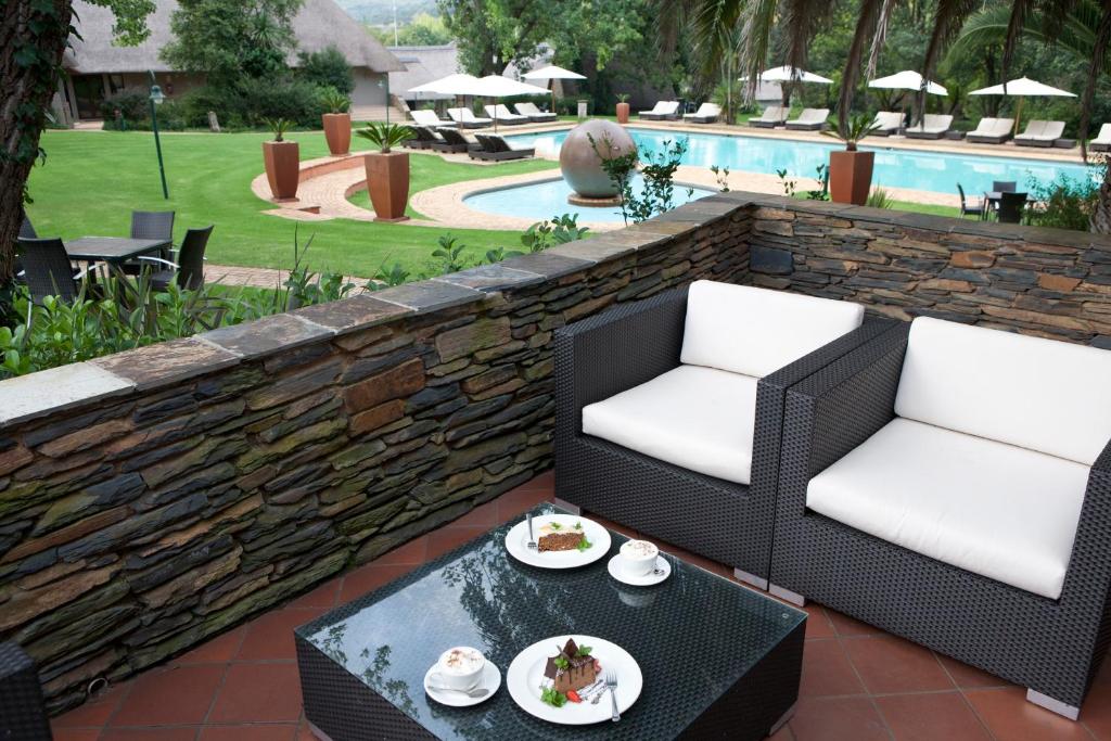 patio z 2 krzesłami i stołem z jedzeniem w obiekcie Valley Lodge & Spa w mieście Magaliesburg