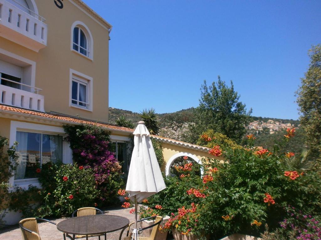 a table with an umbrella in front of a building at Hôtel Paradis in Bormes-les-Mimosas