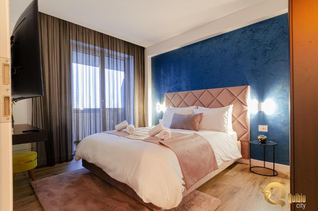 - une chambre avec un grand lit et un mur bleu dans l'établissement Quibio City, à Braşov