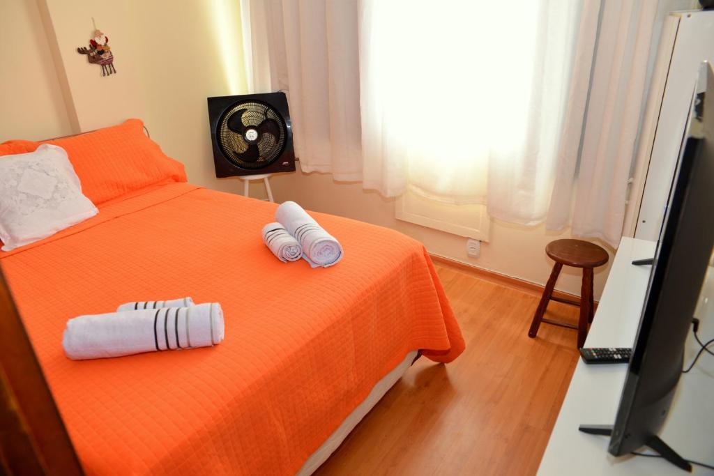 a bedroom with an orange bed with two towels on it at Studio Reformado e Completo em área nobre do Flamengo! in Rio de Janeiro