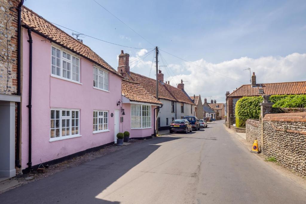 a street in a small town with pink houses at Mariners Hard, Cley-Next-The-Sea in Cley next the Sea