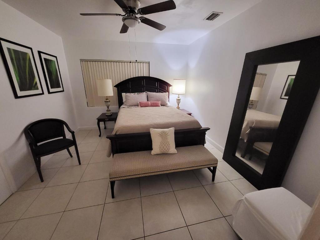 1 dormitorio con cama, espejo y silla en Royal Poinciana Stay en Miami