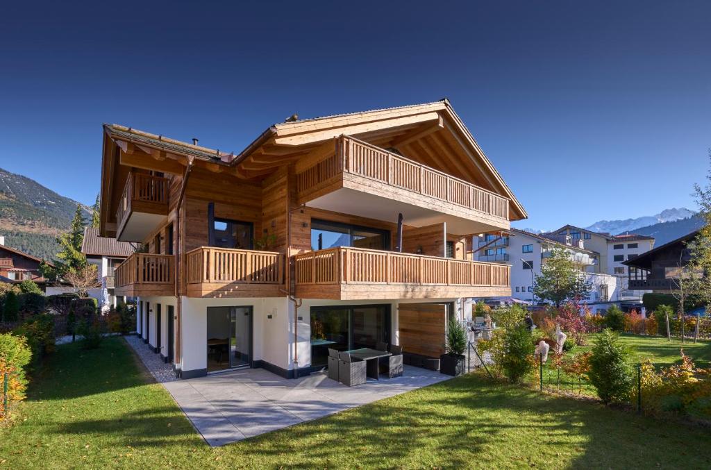 uma casa de madeira com uma varanda e um quintal em Chalet Alpenspirit em Garmisch-Partenkirchen