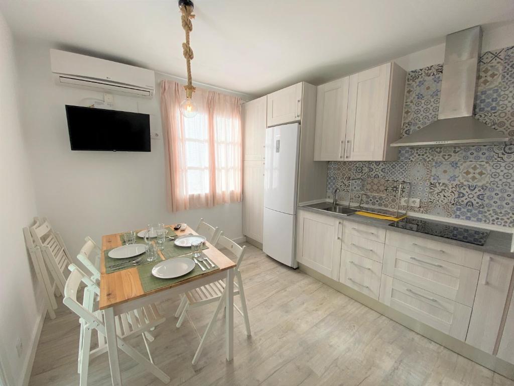 una cocina con mesa y sillas y una cocina con armarios blancos. en Benlloch Silence, en Valencia