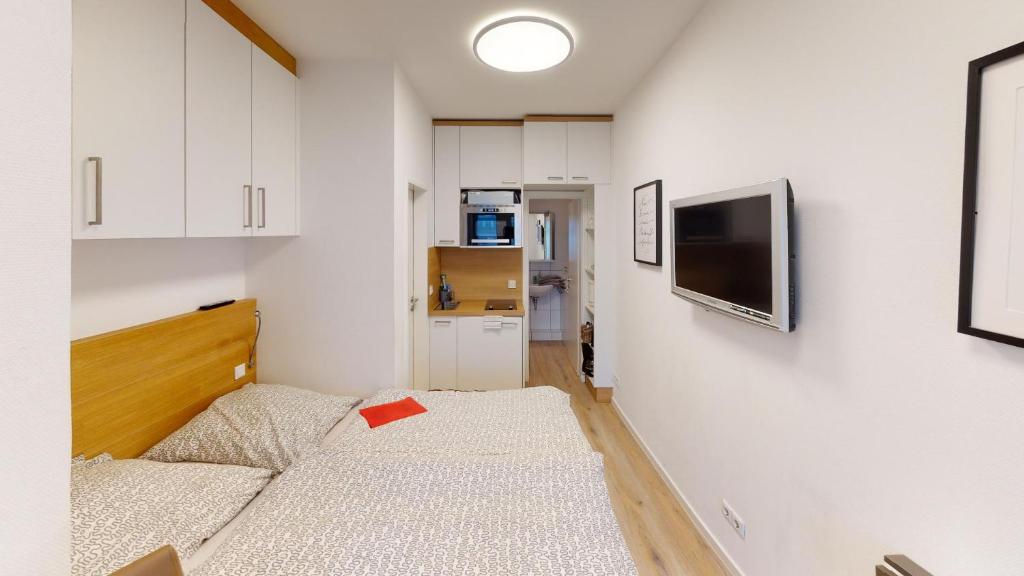 een kleine kamer met een bed en een tv aan de muur bij Alte Teestube W 70 in Norderney