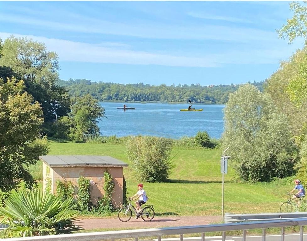dos personas montando en bicicleta en un camino cerca de un lago en Appartamento Bellavista - Fronte Lago di Varese en Gavirate