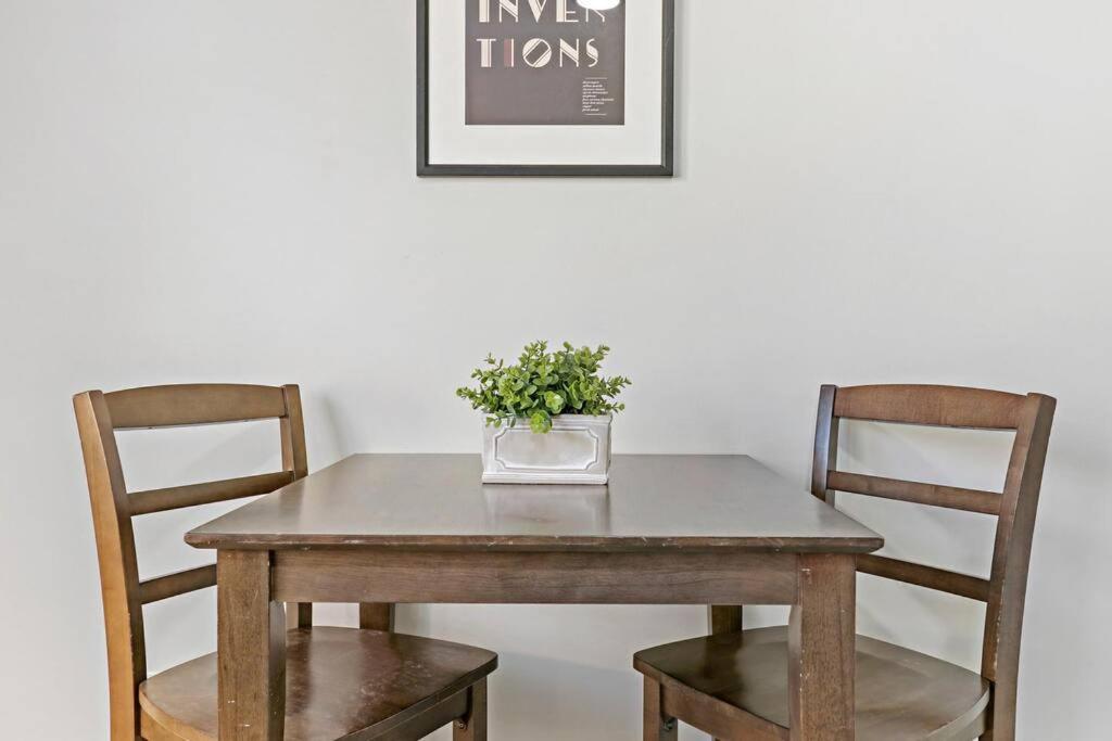 a wooden table with two chairs and a vase with a plant at Appealing 1BR Apartment in Portage Park - Montrose 2S in Chicago