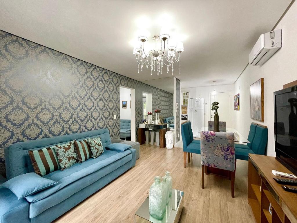 uma sala de estar com um sofá azul e uma sala de jantar em Loft Gramado - Rua Tia Rita Junto aos principais Fondues em Gramado