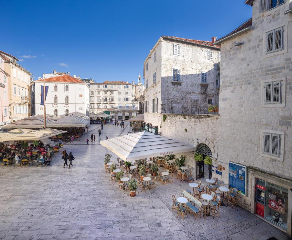 une rue de la ville avec des tables, des chaises et des bâtiments dans l'établissement Judita Palace Heritage Hotel, à Split