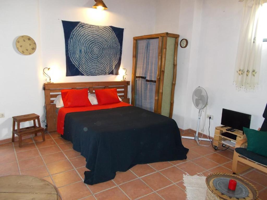 Un dormitorio con una cama con almohadas rojas. en La Tierra Verde STUDIO, en Alcuéscar