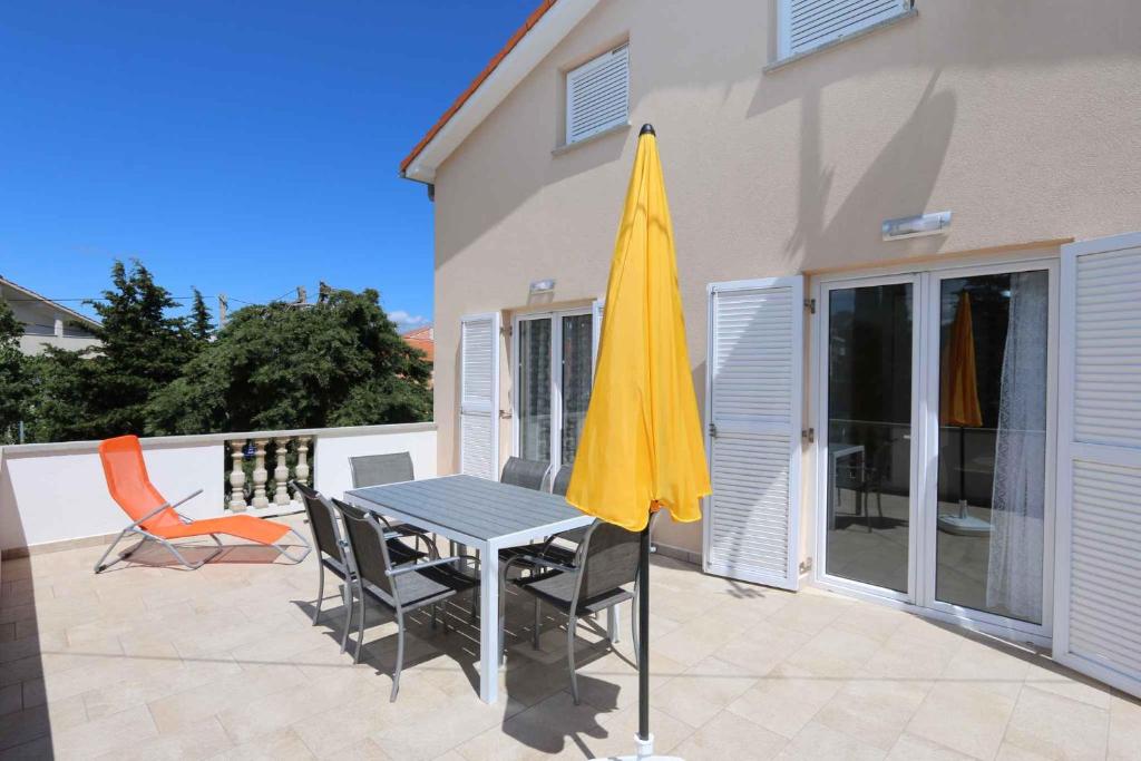 a table and chairs with a yellow umbrella on a patio at Apartment in Silo - Insel Krk 41833 in Šilo