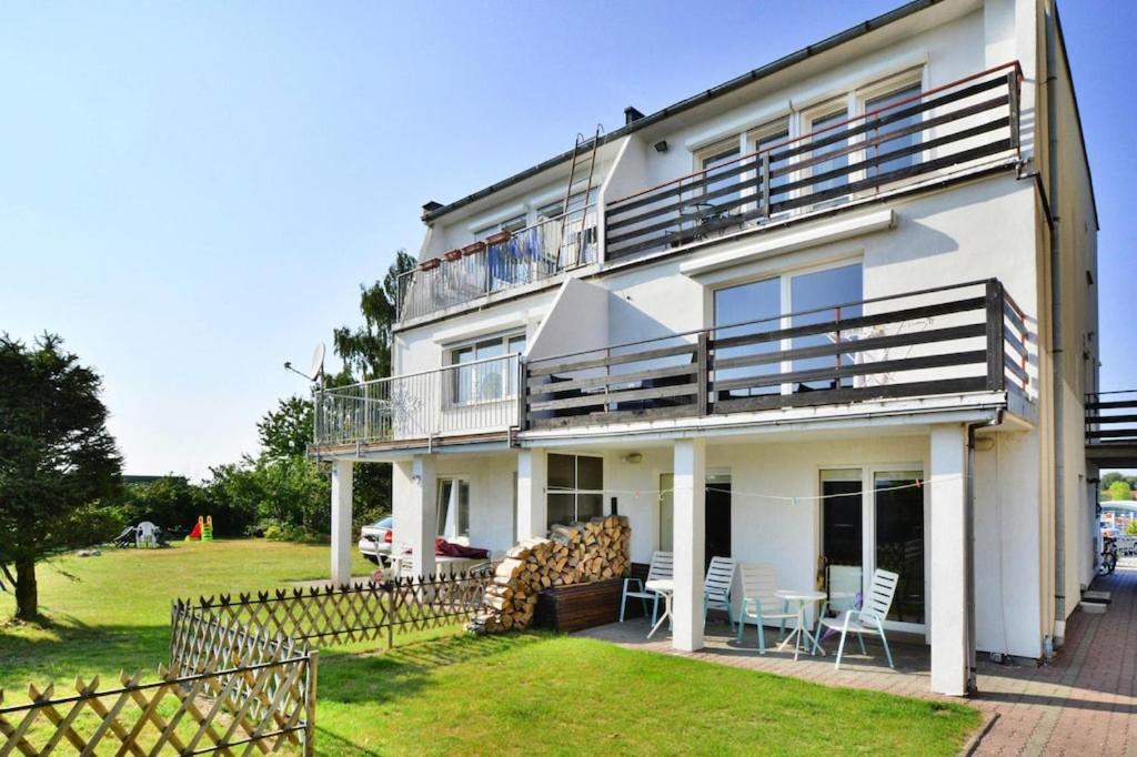 a white house with a balcony and a lawn at holiday home, Ustronie Morskie in Ustronie Morskie