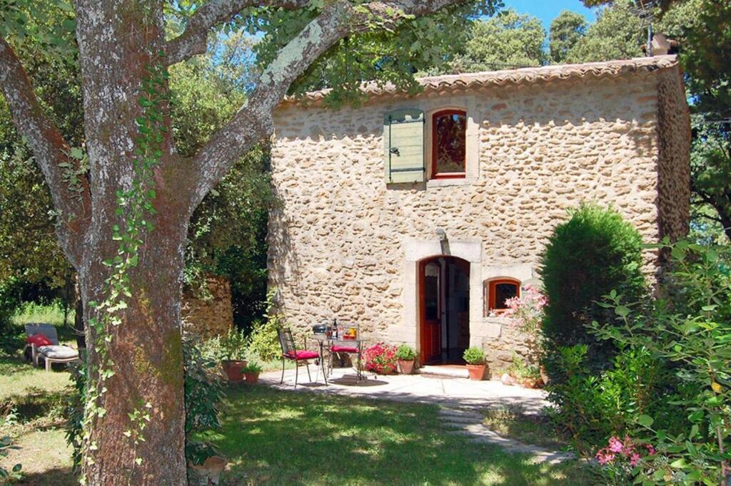 a small stone house with a table and chairs in a yard at holiday home, Grignan in Gourdon