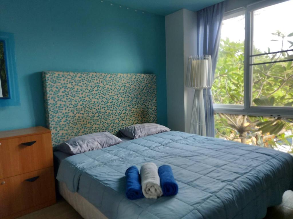 une chambre avec un lit aux murs bleus et une fenêtre dans l'établissement Atlantis Condo Resort Атлантис кондо резорт, à Jomtien Beach
