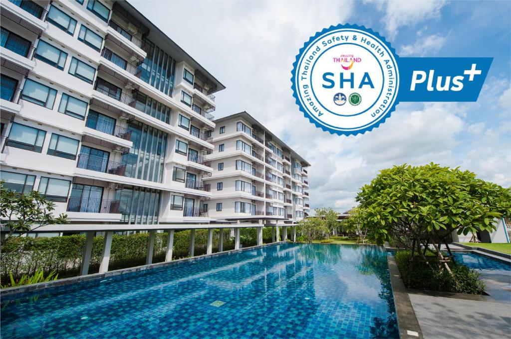 un hotel con piscina frente a un edificio en Burgundy Residence 304 en Si Maha Phot