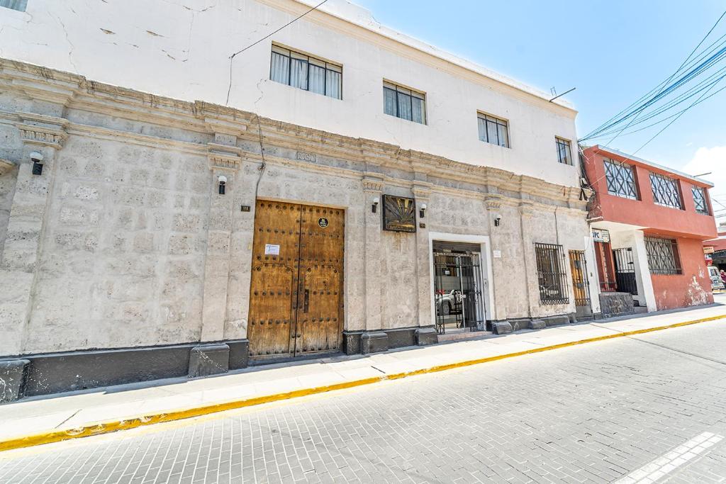 un antiguo edificio de piedra con puertas de madera en una calle en Hotel La Posada Del Sol, en Arequipa