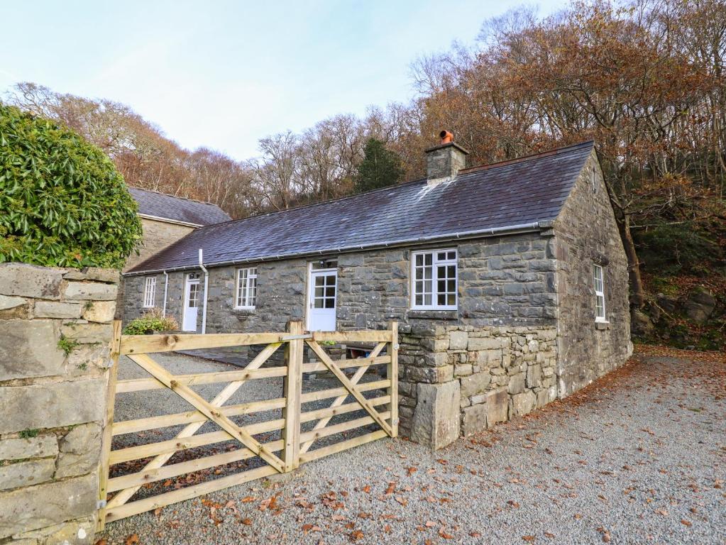 a stone barn with a wooden gate in front of it at Farchynys Court Cottage in Penmaenpool