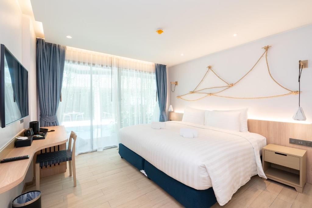 Pokój hotelowy z dużym łóżkiem i biurkiem w obiekcie Panwaburi Beachfront Resort - SHA Extra Plus w mieście Panwa Beach