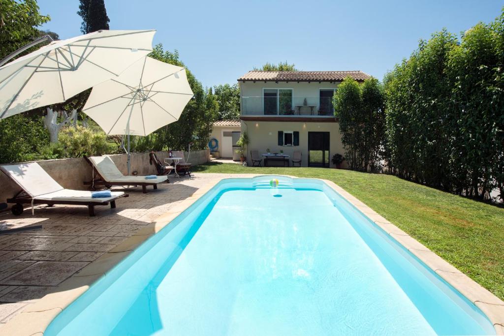 - une piscine avec un parasol et une maison dans l'établissement Spitaki Pool House, à Corfou
