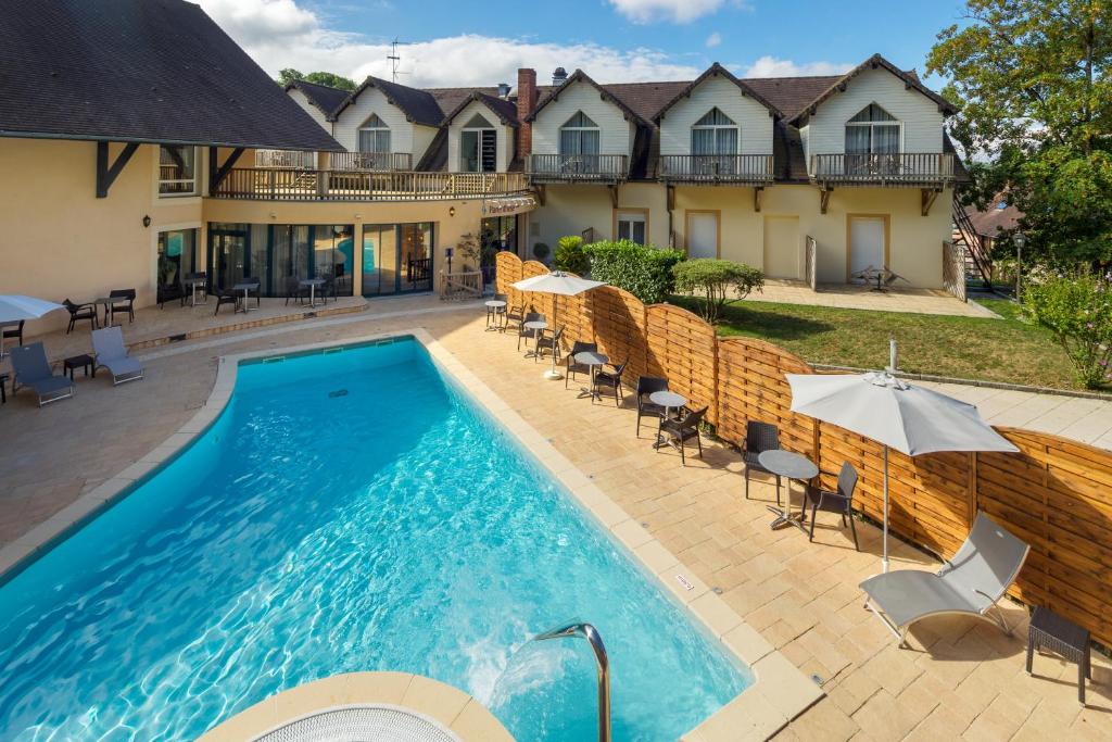 a pool with chairs and umbrellas in front of a house at Logis Hôtel Parenthèse, Restaurant & Spa in Chille